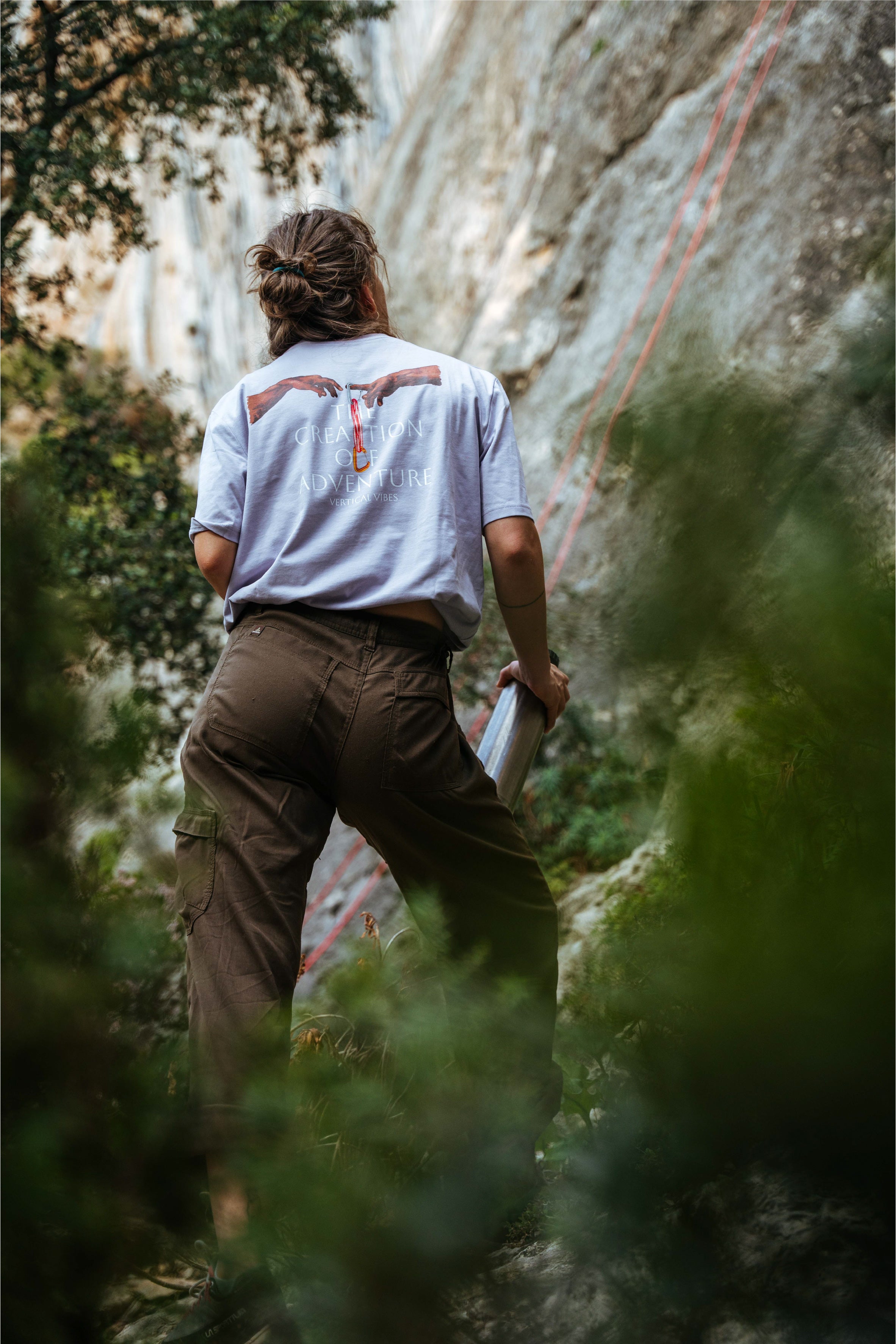 Female climber looking at route with lavender the creation of adventure tshirt by vertical vibes